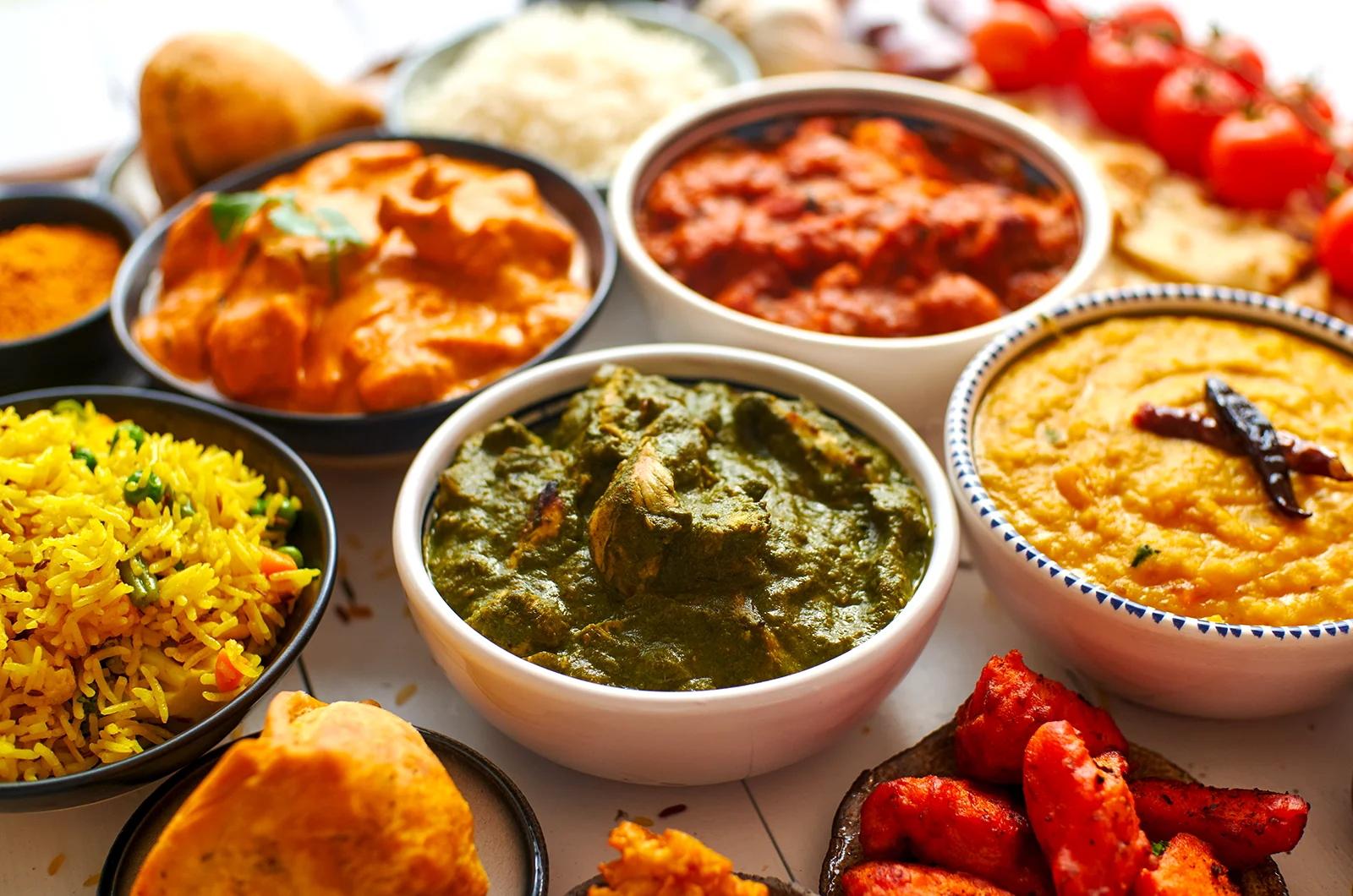 Assorted Bangladeshi dishes including curries, rice, lentils, and naan.